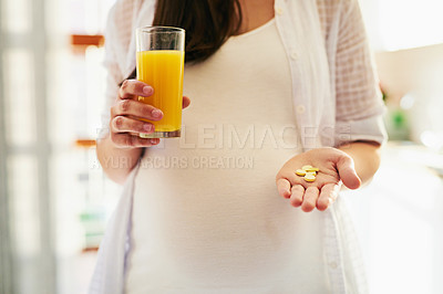 Buy stock photo Shot of a pregnant woman taking medication with orange juice at home