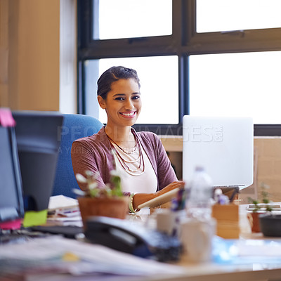 Buy stock photo Shot of a young woman working on her laptop in the office and looking at the camera