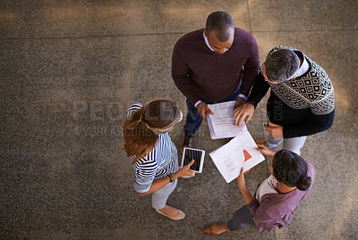 Buy stock photo High angle shot of a group of work colleagues brainstorming and coming up with ideas in a circle in the office