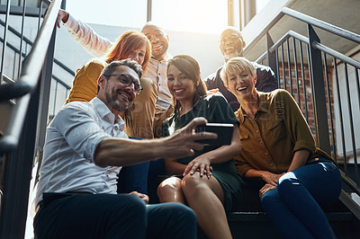 Buy stock photo Cropped shot of a group of business colleagues sitting outside on steps and taking a group photo together