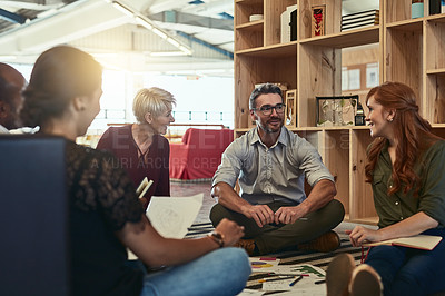 Buy stock photo Cropped shot of a group of business colleagues in the office sitting on the floor and discussing ideas