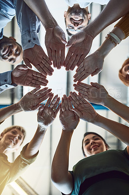 Buy stock photo Low angle shot of a group of colleagues joining their hands in solidarity at work
