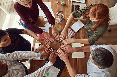 Buy stock photo High angle shot of a group of colleagues joining their hands in solidarity during a meeting in a modern office