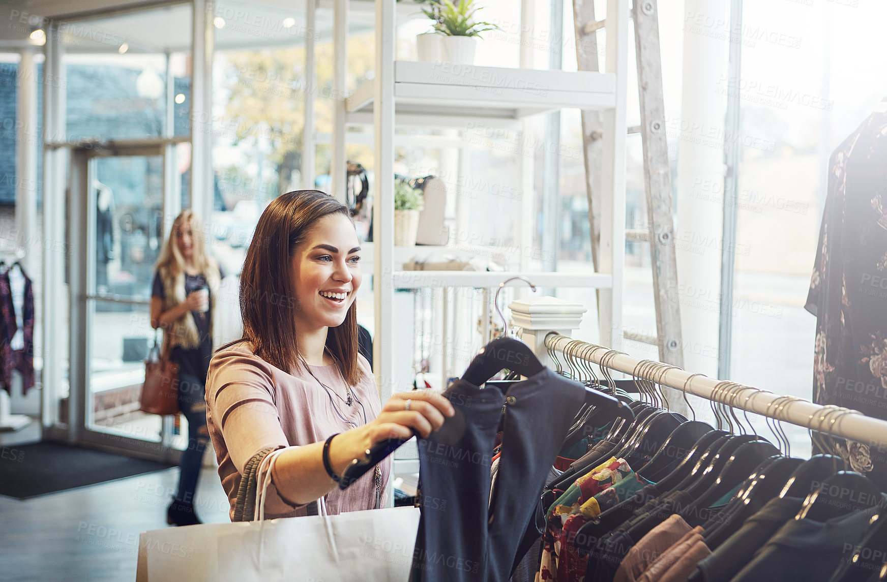 Buy stock photo Shot of a young woman holding up an item that she picked out in a clothing store