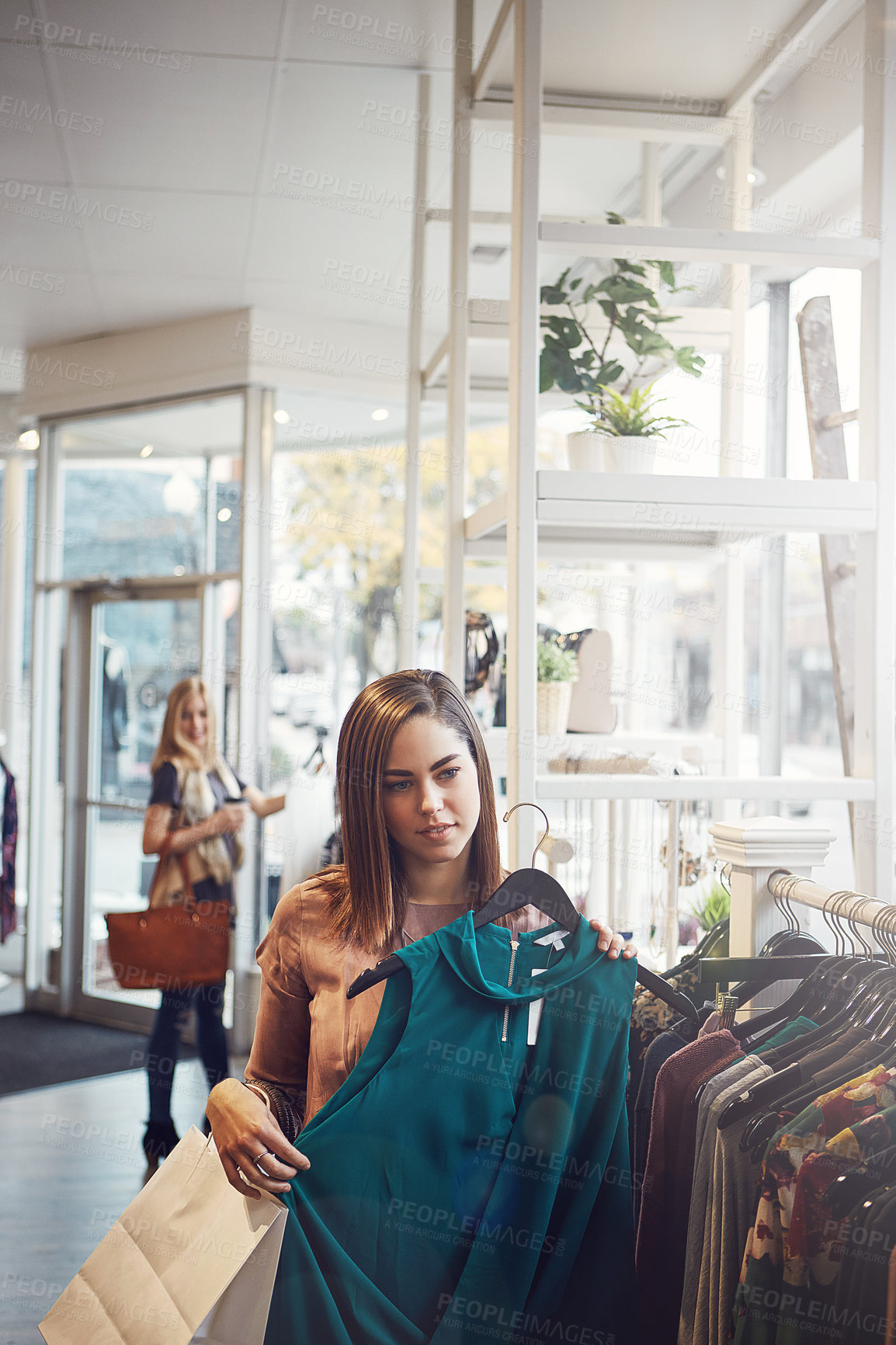 Buy stock photo Shot of a young woman holding up an item that she picked out in a clothing store