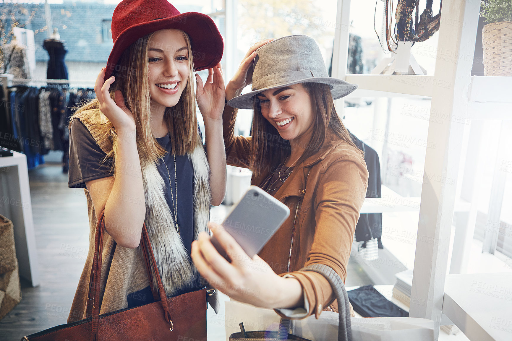 Buy stock photo Cropped shot of two young girlfriends snapping selfies while out on a shopping spree