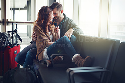 Buy stock photo Shot of a young couple sitting in an airport with their luggage and embracing each other