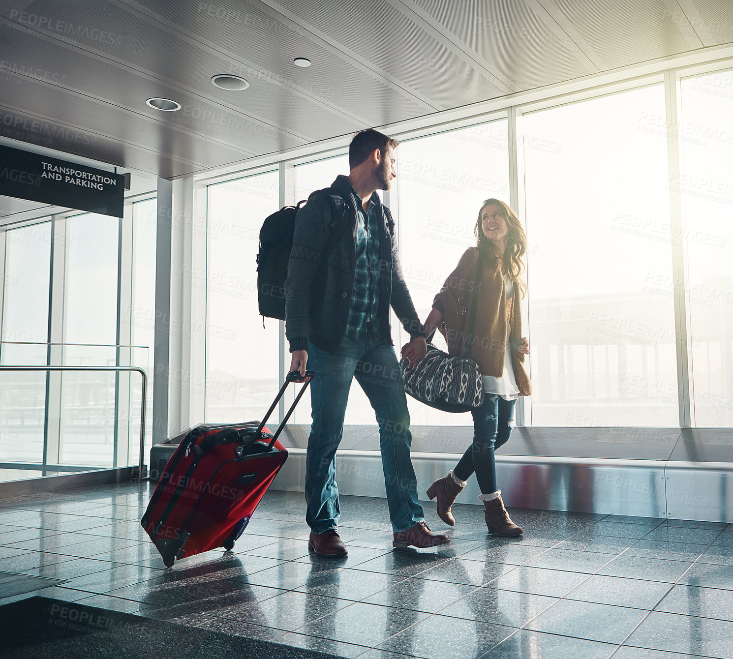 Buy stock photo Walking, couple and holding hands with suitcase, man and woman in airport, journey and smile for vacation. People, together and happiness for holiday, trip or travel for flight, excited and honeymoon