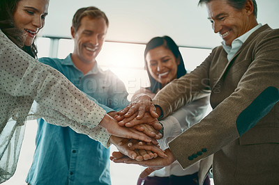 Buy stock photo Cropped shot of a motivated group of businesspeople standing in the office with their hands in a huddle