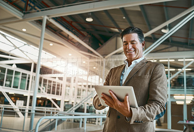 Buy stock photo Shot of a mature businessman standing in the office and making notes on his tablet for the business