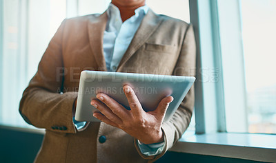 Buy stock photo Cropped shot of an unrecognizable businessman standing in the office and making notes on his tablet