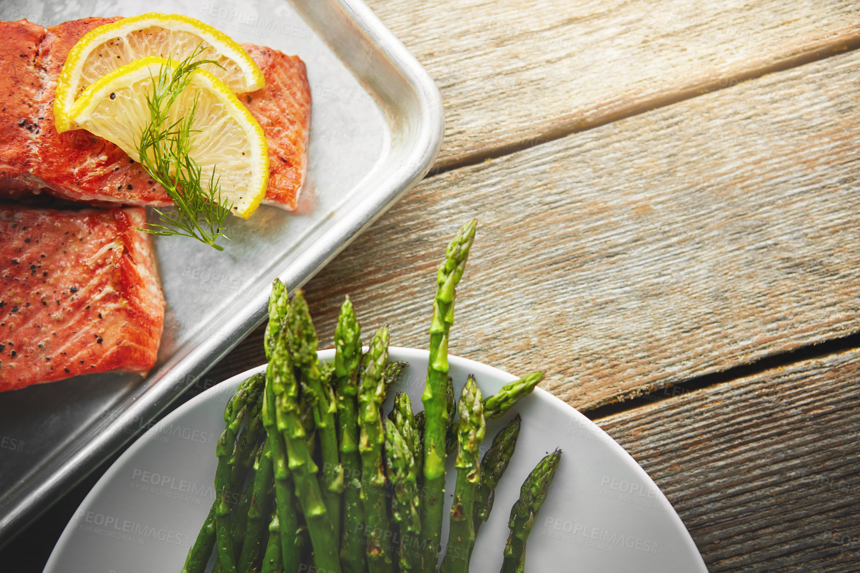 Buy stock photo Shot of a dish with fish and a plate of asparagus on a table