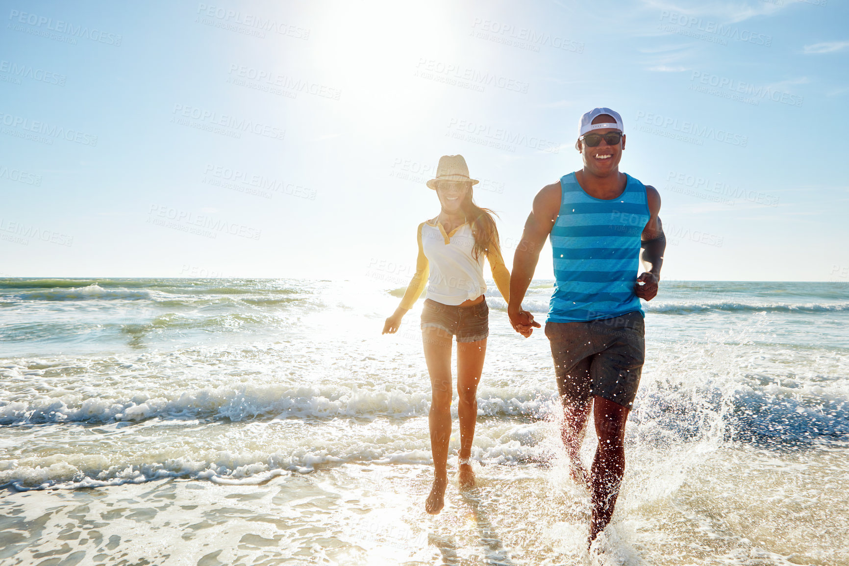 Buy stock photo Couple, walking and water splash at beach for outdoor romance, holiday and vacation in summer. Excited people holding hands with love, fun and travel adventure with health and wellness in portrait