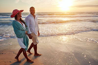 Buy stock photo Shot of a young couple taking a romantic stroll on the beach at sunset