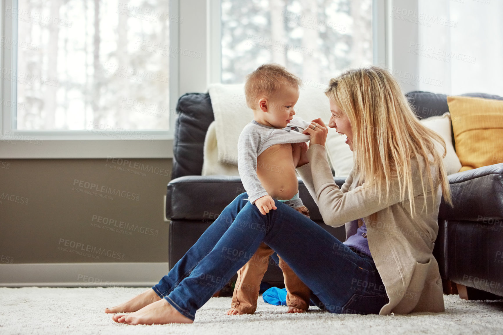 Buy stock photo Home, fun and dressing of baby by mom, living room and playful with son, love and care in apartment. House, mother and toddler in lounge, clothes and together on floor, happiness and wellness for boy