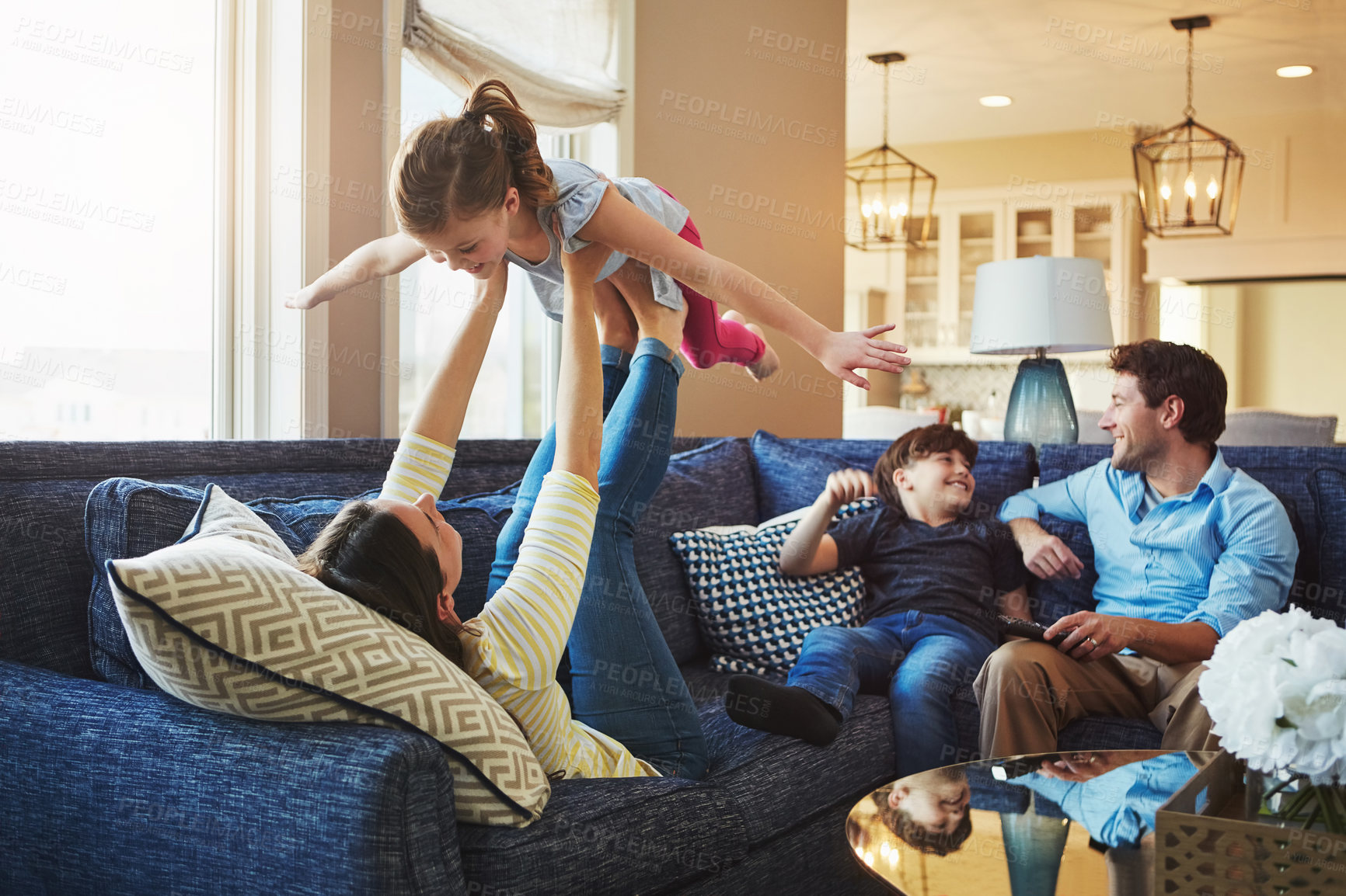 Buy stock photo Airplane, funny and family on sofa in home relaxing with care, happiness and love together. Smile, bonding and girl child with flying and playing with mom, brother and dad or people on couch in house