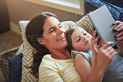 Buy stock photo Shot of a mother and her daughter using a digital tablet together on the sofa at home