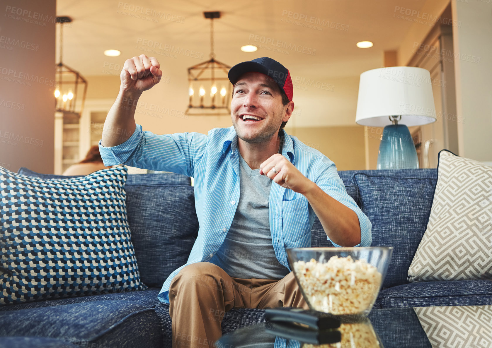 Buy stock photo Happy, man and celebration in home on sofa on day off with watching sports game, challenge and fun. Living room, couch and excited or smile with fist or popcorn, win and tournament for entertainment