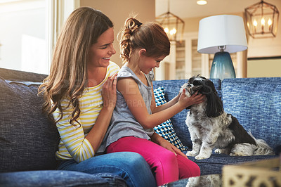 Buy stock photo Shot of a mother and her daughter playing with their dog at home