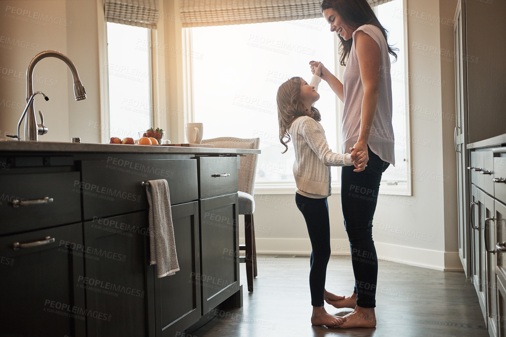 Buy stock photo Mother, daughter and dancing in kitchen, love and happiness in house, care and feet of kid on mom. Home, fun and smile for bonding in apartment, teaching and morning for support and holding hands