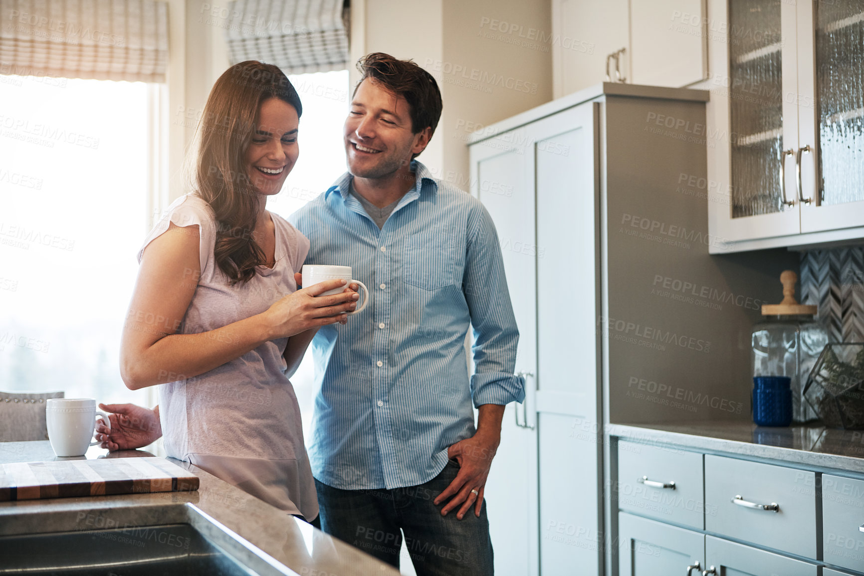 Buy stock photo Shot of a happy married couple chatting while drinking coffee together in their kitchen