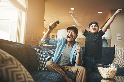Buy stock photo Shot of an enthusiastic father and son watching a sports match on tv at home