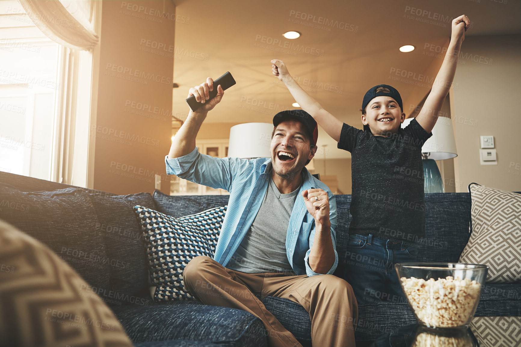 Buy stock photo Television, popcorn and man with child in celebration for network, streaming and bonding at home. Dad, son and excited with tv remote in fist for sports, winning and watching live broadcast together