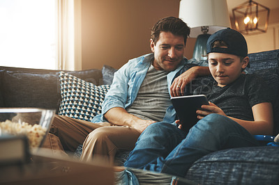 Buy stock photo Shot of a father and his son using a digital tablet together on the sofa at home