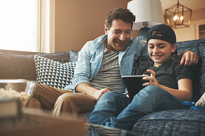 Buy stock photo Shot of a father and his son using a digital tablet together on the sofa at home