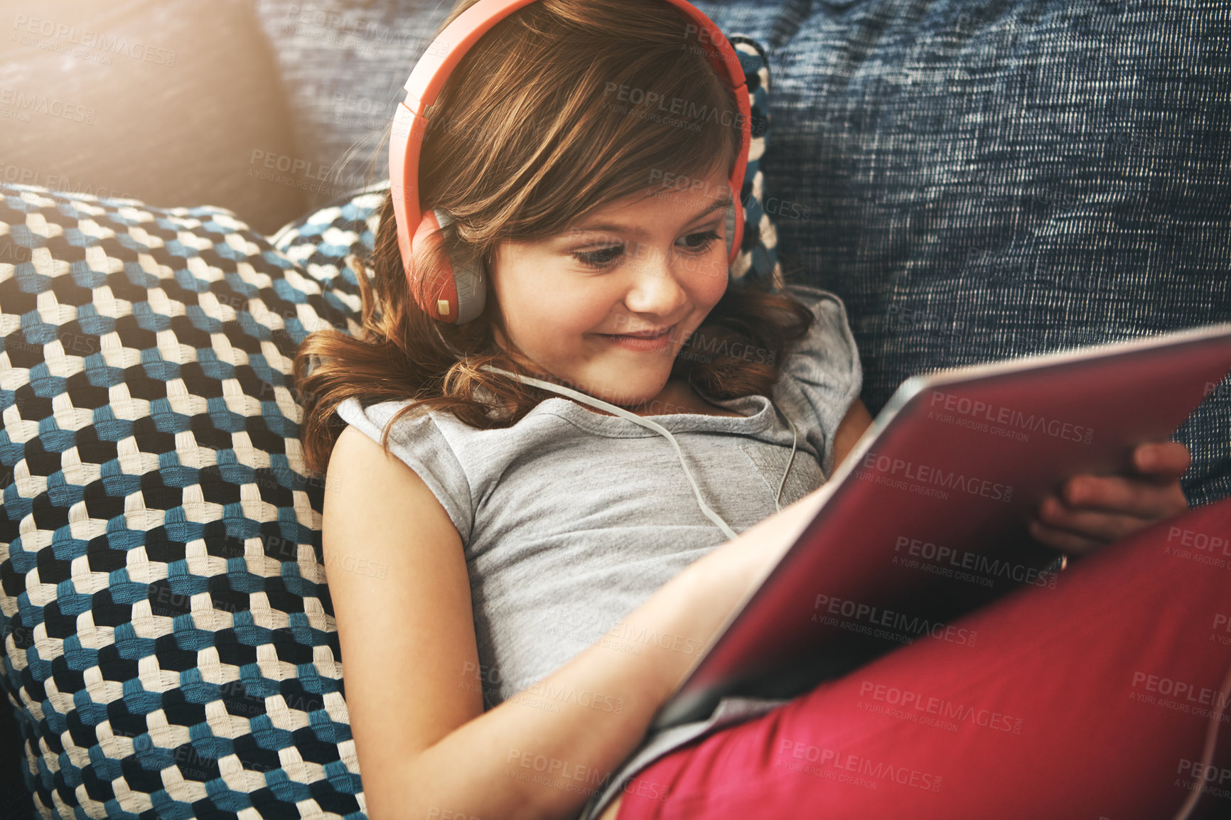 Buy stock photo Shot of a little girl wearing headphones while using a digital tablet at home