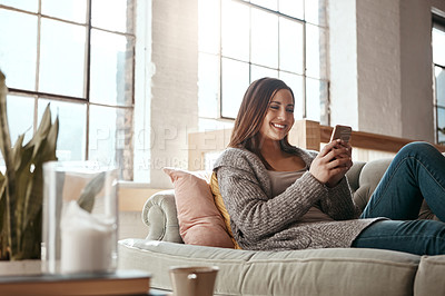 Buy stock photo Happy, woman and phone for social media on a sofa, texting and chatting on dating app in her home. Girl, smartphone and text conversation in a living room, smile and relax while streaming and resting