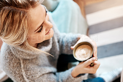 Buy stock photo Shot of a young woman relaxing on the sofa at home with a warm beverage