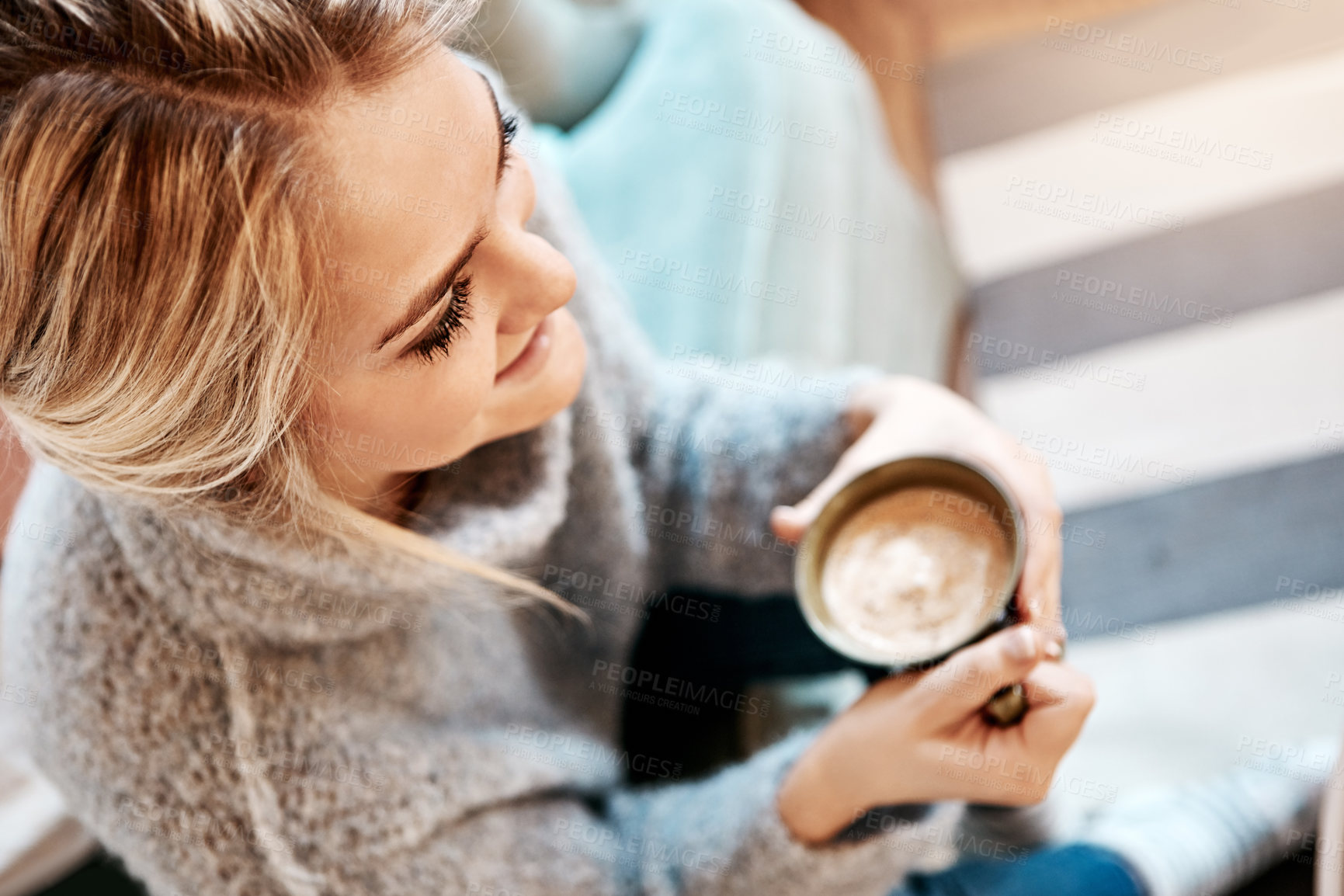 Buy stock photo Shot of a young woman relaxing on the sofa at home with a warm beverage