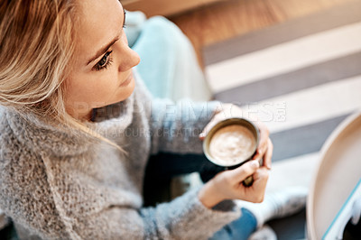 Buy stock photo Shot of a young woman relaxing on the sofa at home with a warm beverage