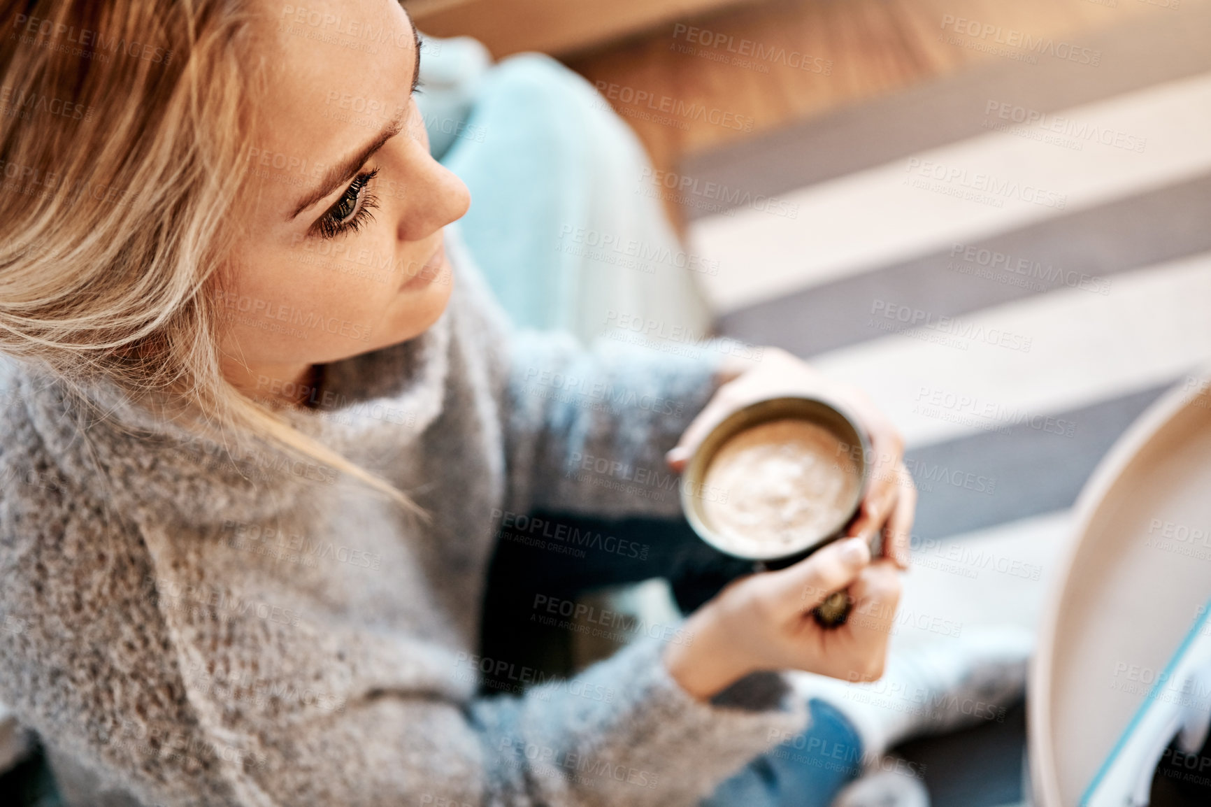 Buy stock photo Shot of a young woman relaxing on the sofa at home with a warm beverage