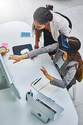 Buy stock photo High angle shot of a young businesswoman using a VR headset while being assisted by a female colleague