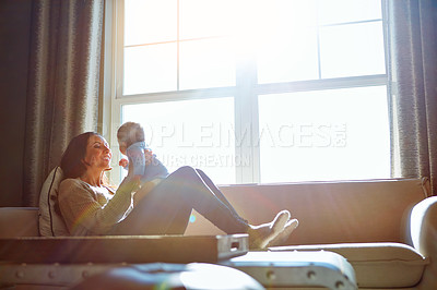 Buy stock photo Shot of a young woman bonding with her baby boy on the sofa at home