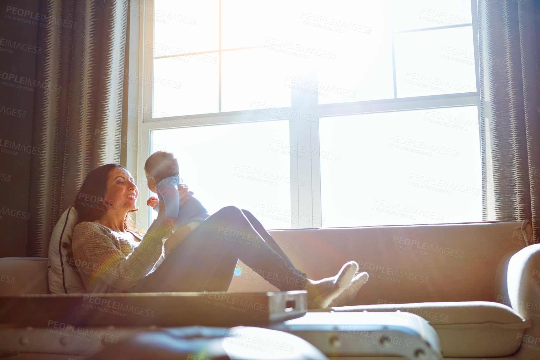 Buy stock photo Shot of a young woman bonding with her baby boy on the sofa at home