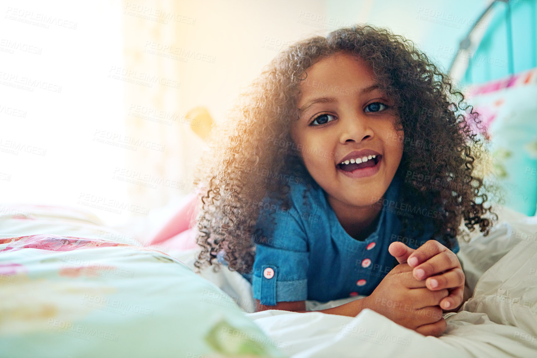 Buy stock photo Portrait of a cheerful little girl relaxing on her bed at home