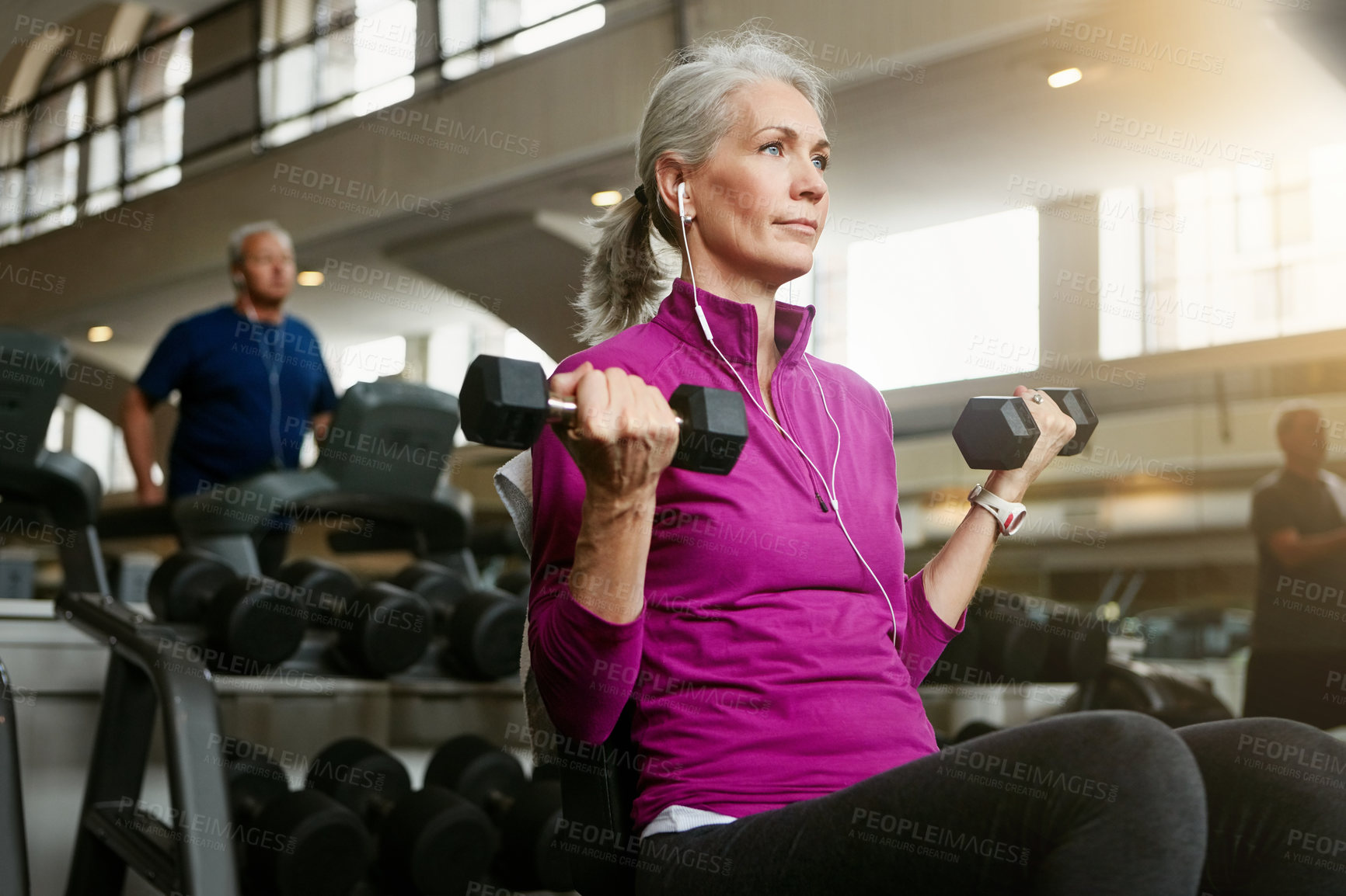 Buy stock photo Dumbbell, music and training with mature woman on bench in gym for physical fitness or workout. Exercise, health and weight with confident athlete person in performance club for active challenge