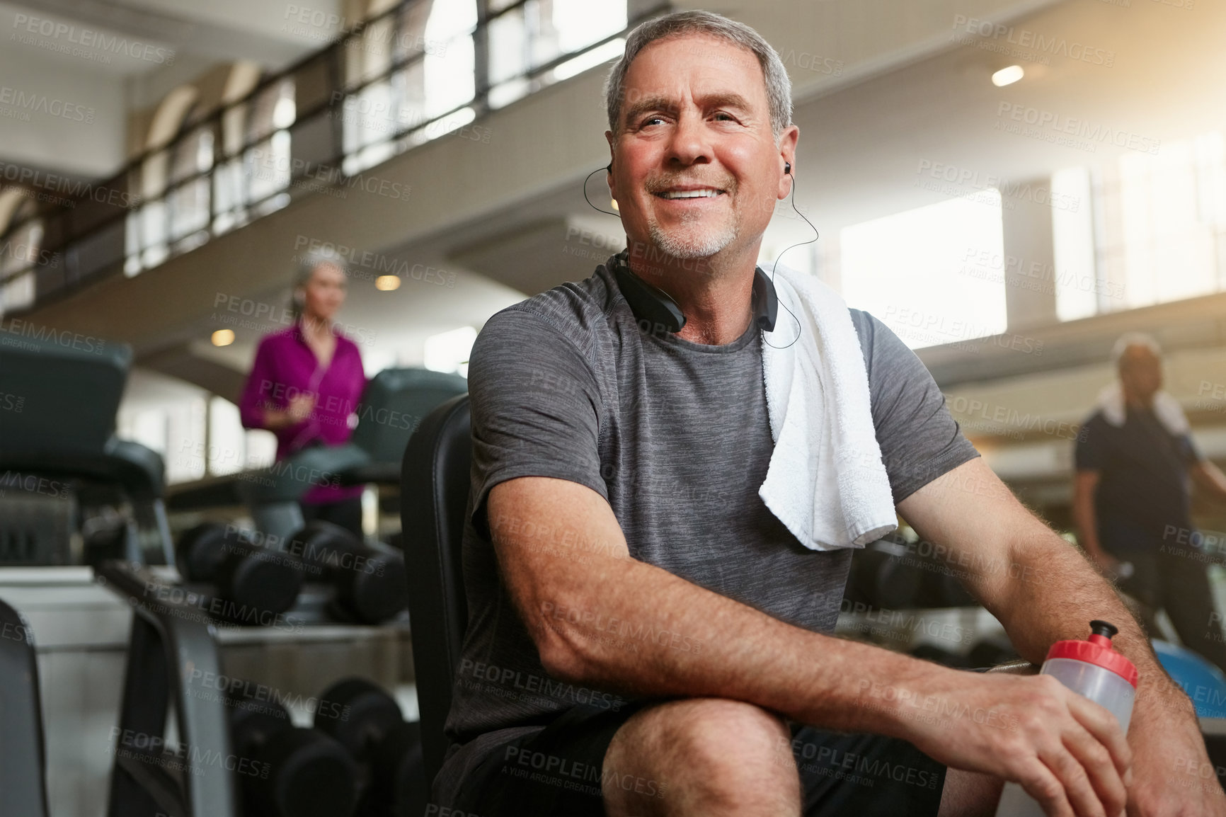 Buy stock photo Shot of a senior man holding a water bottle and taking a break from his workout at the gym