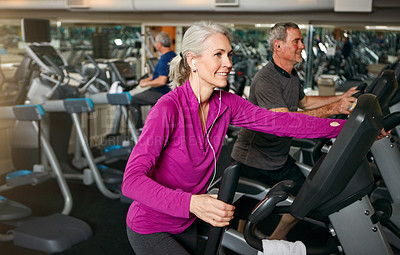 Buy stock photo Shot of a happy senior woman working out on an elliptical trainer at the gym