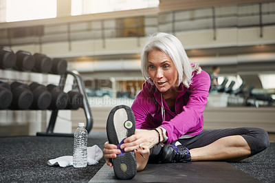 Buy stock photo Feet, stretching and mature fitness woman on a gym floor for body warm up, training and morning cardio with water. Sports, wellness and female athlete with ground cooling exercise after club workout