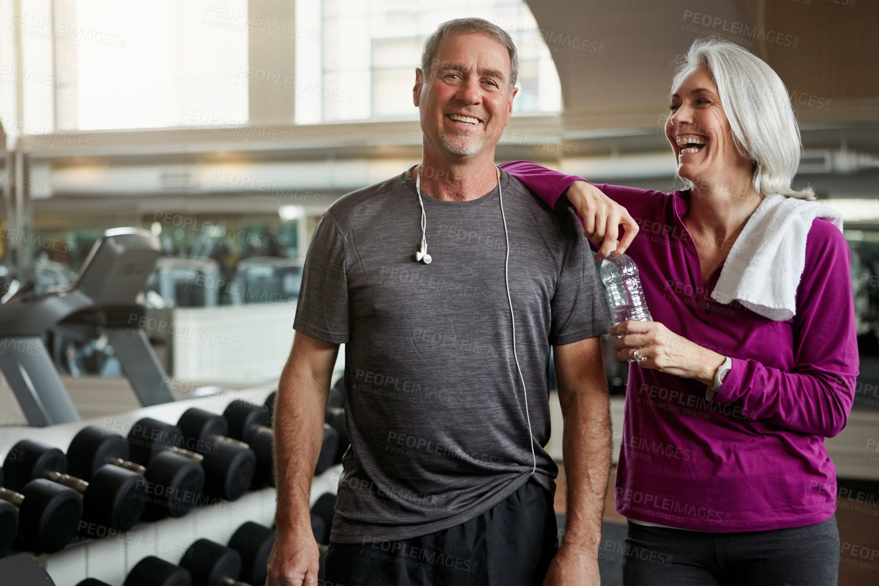 Buy stock photo Mature couple, portrait and bottle with gym, smile and dumbbell for training, conversation and exercise. Man, woman and happy together for health, workout and motivation with water at wellness club