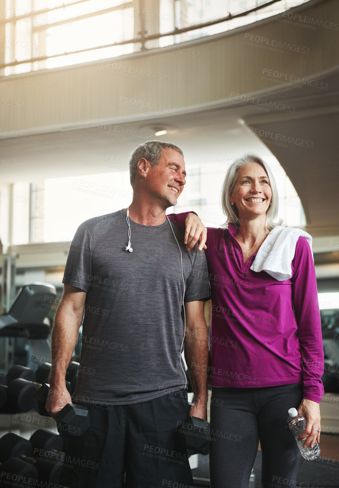 Buy stock photo Shot of a senior married couple smiling and taking a break from their workout at the gym