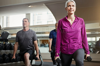 Buy stock photo Shot of a senior group of woman and men working out with weights together at the gym
