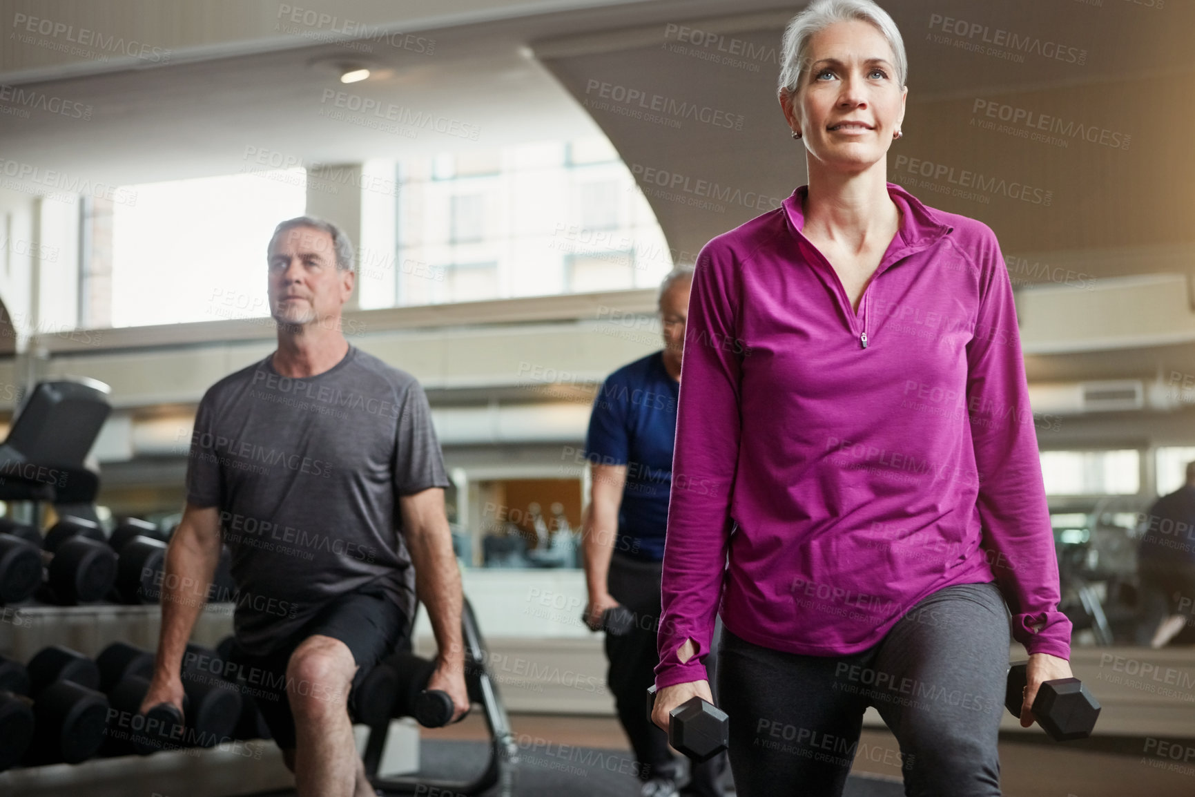 Buy stock photo Shot of a senior group of woman and men working out with weights together at the gym