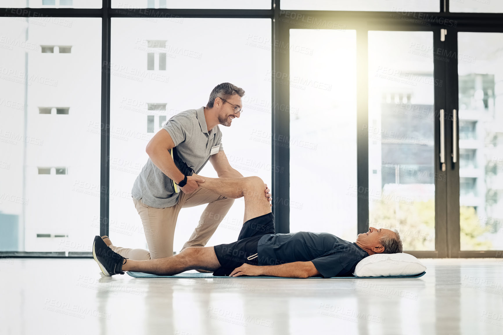 Buy stock photo Shot of a friendly physiotherapist helping his mature patient to stretch at a rehabilitation center