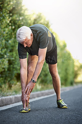 Buy stock photo Shot of a senior man warming up before a run outside