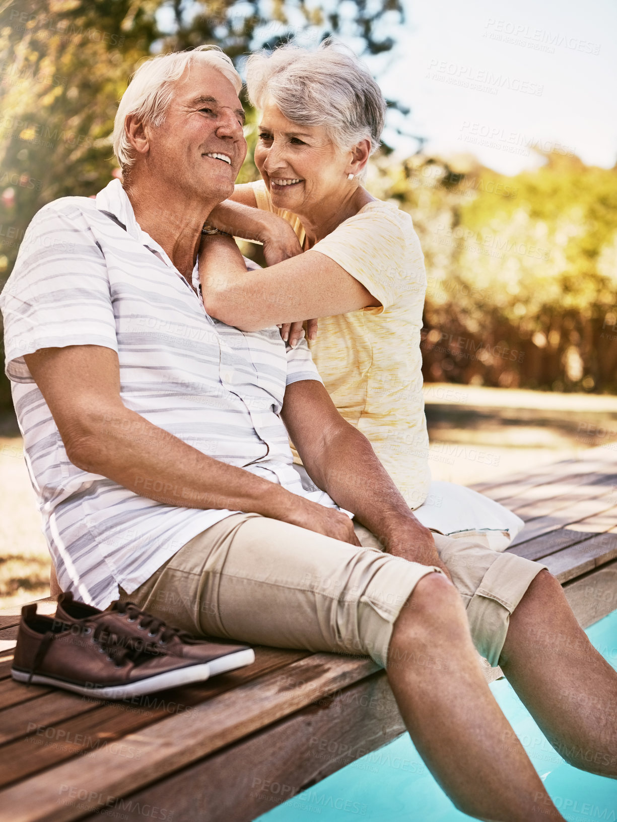 Buy stock photo Shot of a happy senior couple relaxing together by the poolside